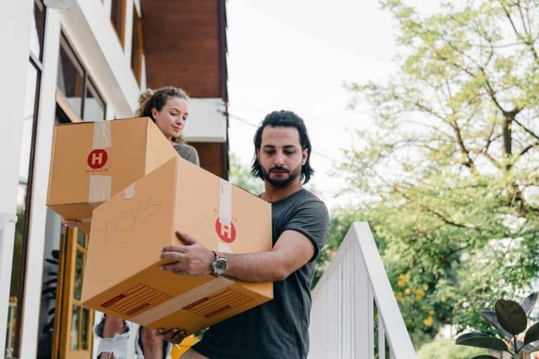 Couple-carrying-boxes-on-steps-while-moving-out-of-house